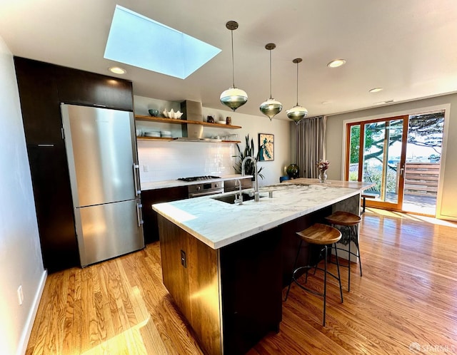 2543 44th Ave, San Francisco, CA 94116 - kitchen with freestanding refrigerator, wall chimney exhaust hood, a skylight, a sink, and light wood-style flooring