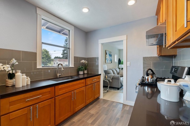 3644 Redding St, Oakland, CA 94619 - kitchen with wood finished floors, extractor fan, brown cabinets, tasteful backsplash, and dark countertops
