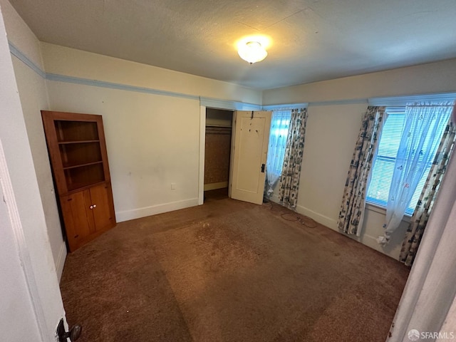 unfurnished bedroom with dark colored carpet and a closet