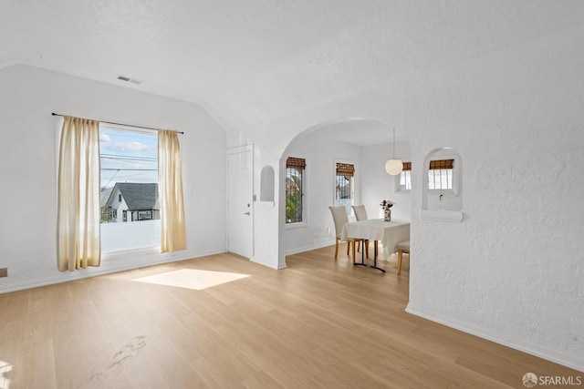 foyer featuring a wealth of natural light, visible vents, arched walkways, and light wood-style flooring