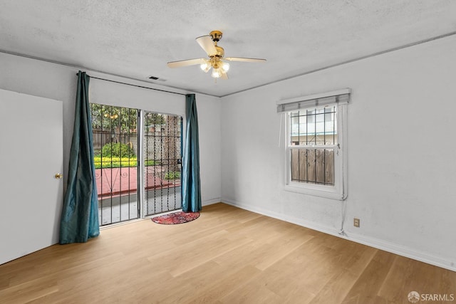 unfurnished room with ceiling fan, wood finished floors, and a textured ceiling