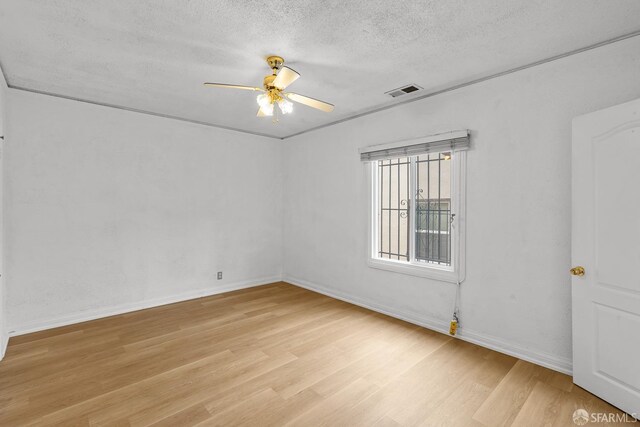 spare room with a textured ceiling, baseboards, light wood-type flooring, and ceiling fan