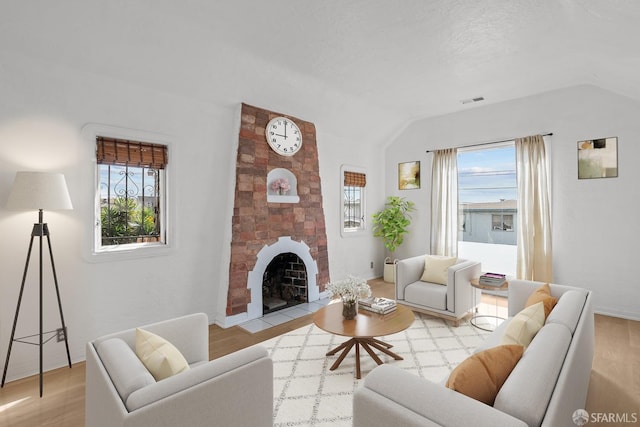 living room featuring light wood-style floors, a fireplace, and vaulted ceiling