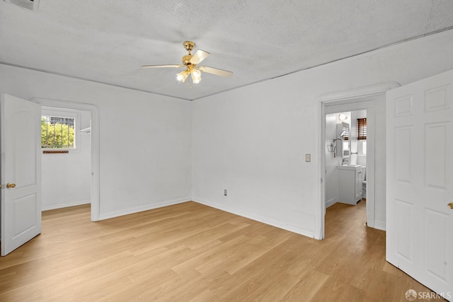 spare room featuring baseboards, light wood-style floors, ceiling fan, and a textured ceiling