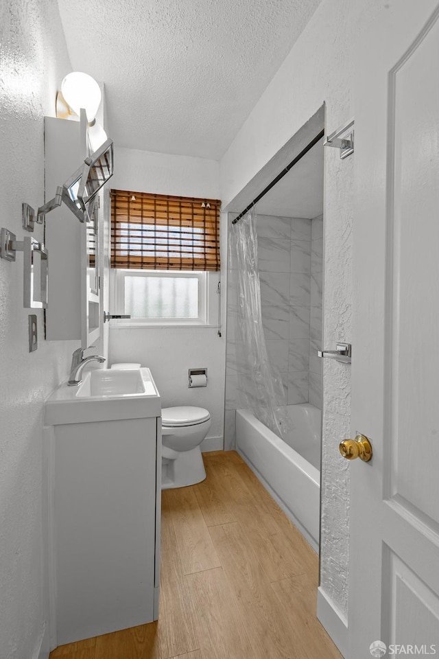 full bath with vanity, wood finished floors, a textured ceiling, toilet, and a textured wall
