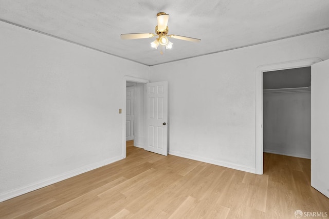 unfurnished bedroom with a spacious closet, light wood-style floors, a closet, and baseboards