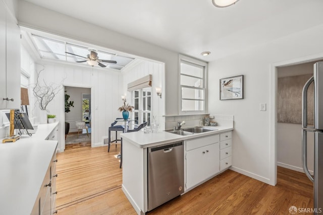 25 Roselyn Ter, San Francisco, CA 94118 - kitchen featuring stainless steel appliances, a sink, light countertops, white cabinetry, and light wood-style floors