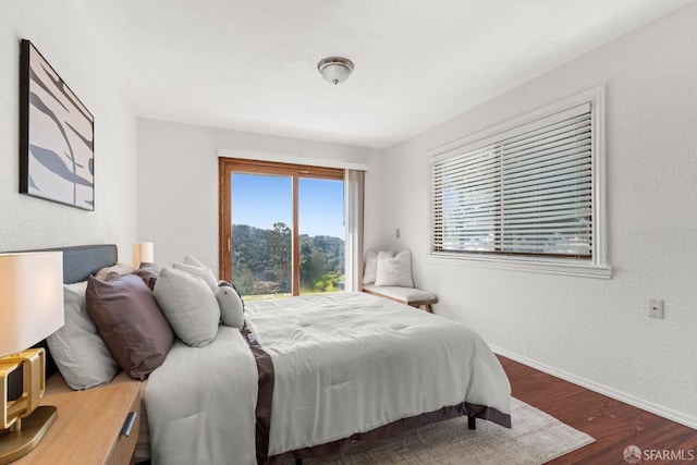 bedroom featuring wood finished floors, baseboards, and a textured wall