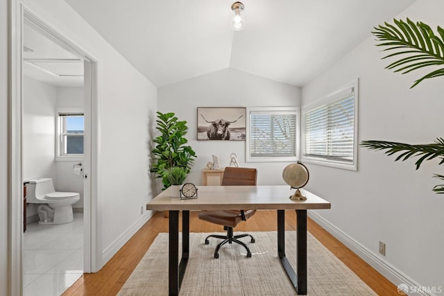 home office with light wood finished floors, a healthy amount of sunlight, and vaulted ceiling