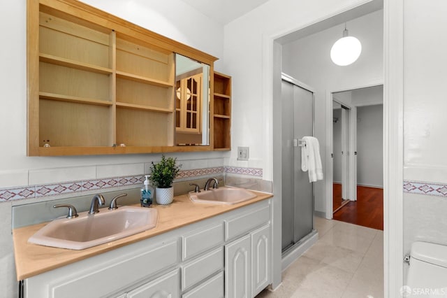 bathroom with double vanity, toilet, a stall shower, and a sink