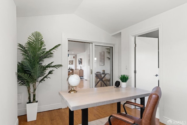 office area featuring lofted ceiling, baseboards, and light wood-type flooring