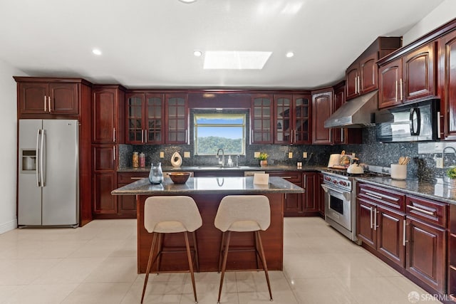 kitchen with under cabinet range hood, a sink, stainless steel appliances, and reddish brown cabinets