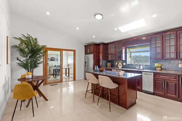 kitchen with appliances with stainless steel finishes, tasteful backsplash, dark brown cabinets, and a center island