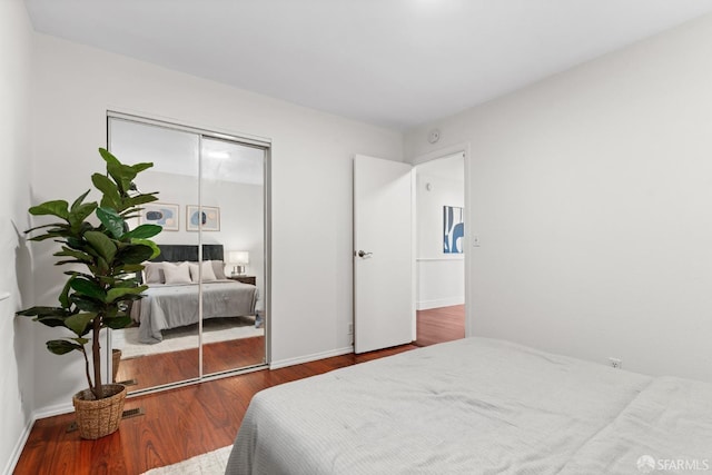 bedroom with wood finished floors, a closet, and baseboards