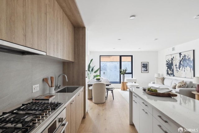 915 N Point St Unit J3, San Francisco, CA 94109 - kitchen with light wood-type flooring, modern cabinets, open floor plan, light stone counters, and exhaust hood