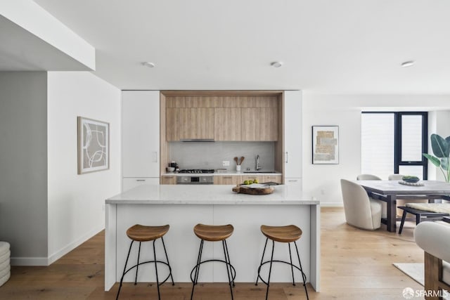 915 N Point St Unit J3, San Francisco, CA 94109 - kitchen with modern cabinets, a breakfast bar, backsplash, and light stone countertops