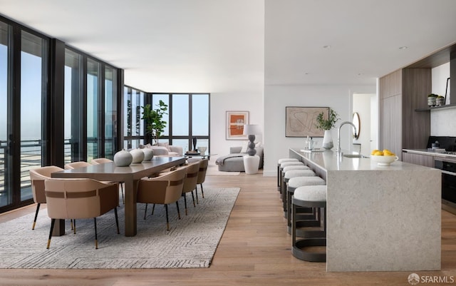 dining area with floor to ceiling windows, sink, and light hardwood / wood-style floors