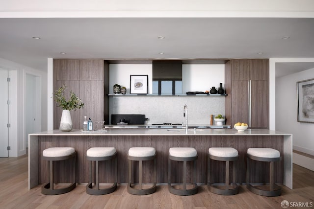 kitchen with tasteful backsplash, sink, a spacious island, and hardwood / wood-style flooring