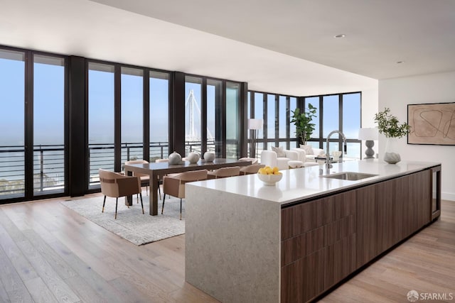 kitchen featuring a wall of windows, a water view, light wood-type flooring, and sink