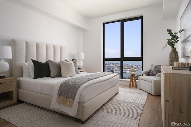 bedroom with a water view and light hardwood / wood-style flooring