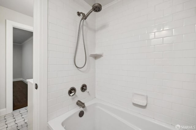 bathroom featuring tile patterned flooring, ornamental molding, and tiled shower / bath