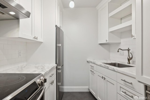 kitchen with decorative backsplash, white cabinetry, light stone counters, and extractor fan