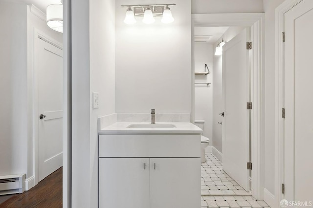 bathroom featuring wood-type flooring, vanity, toilet, and a baseboard radiator