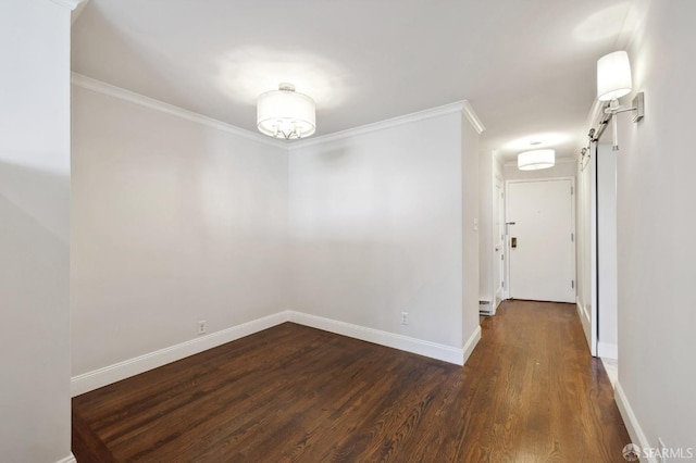 spare room with a barn door, dark wood-type flooring, and crown molding