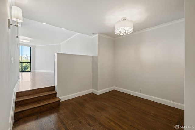 empty room featuring an inviting chandelier, ornamental molding, and dark wood-type flooring