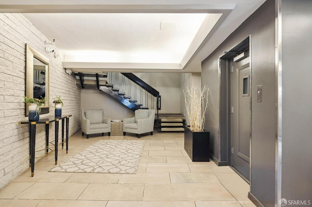 living area featuring a raised ceiling, brick wall, and light tile patterned floors