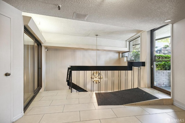 tiled entryway featuring a textured ceiling and a chandelier