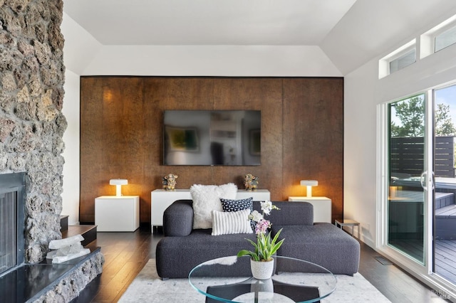 living area featuring wood-type flooring, lofted ceiling, visible vents, and a fireplace