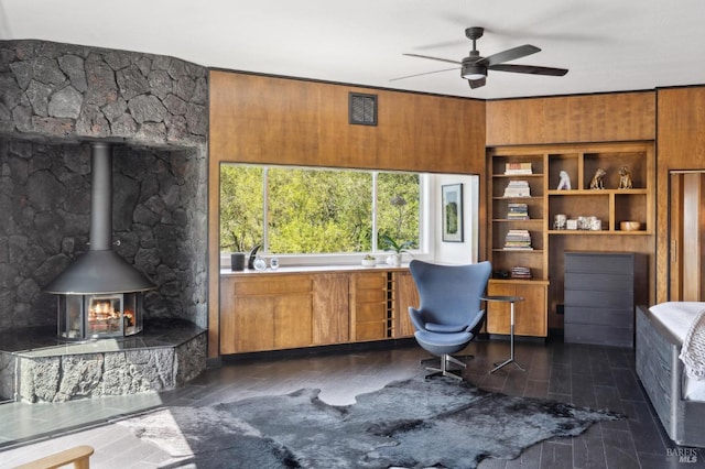 office with a wood stove, a ceiling fan, and dark wood finished floors