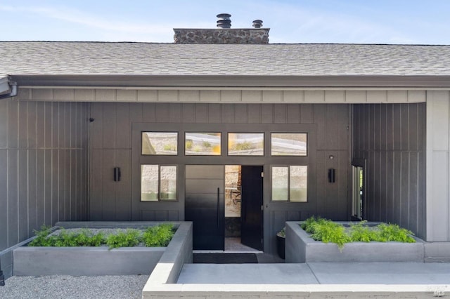 property entrance featuring roof with shingles and a chimney