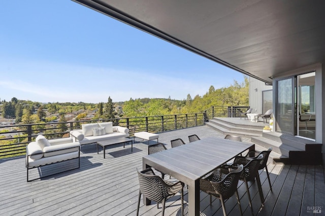 wooden deck with outdoor dining space, a forest view, and an outdoor hangout area