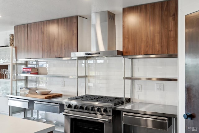 kitchen with brown cabinetry, modern cabinets, wall chimney range hood, and stainless steel range