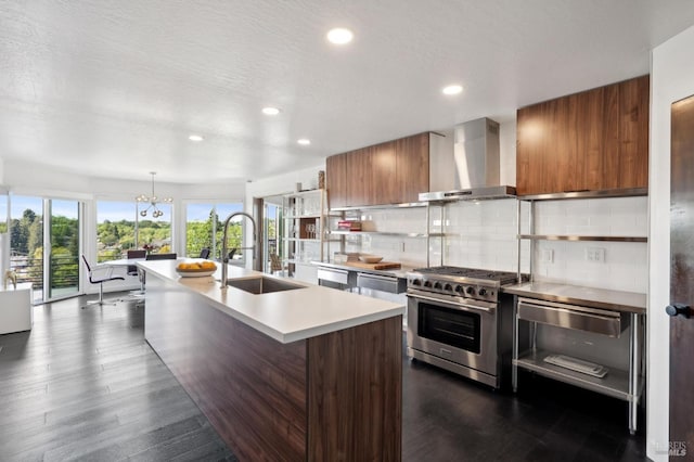kitchen featuring a sink, wall chimney range hood, light countertops, brown cabinets, and high end range