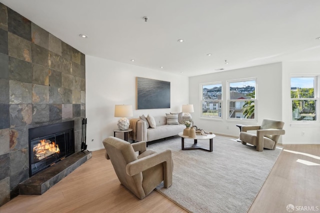 living room with a tile fireplace and light wood-type flooring