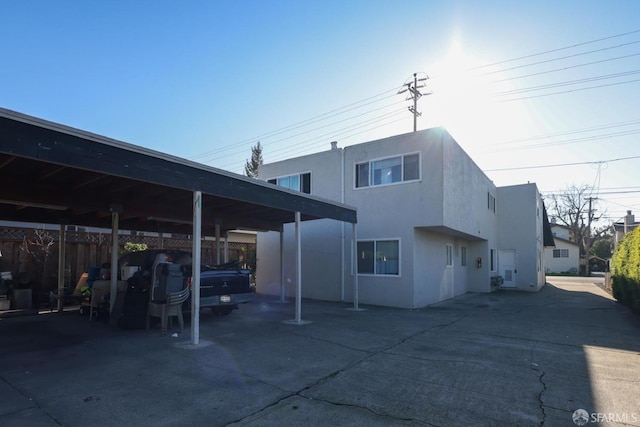 rear view of property with covered parking and stucco siding