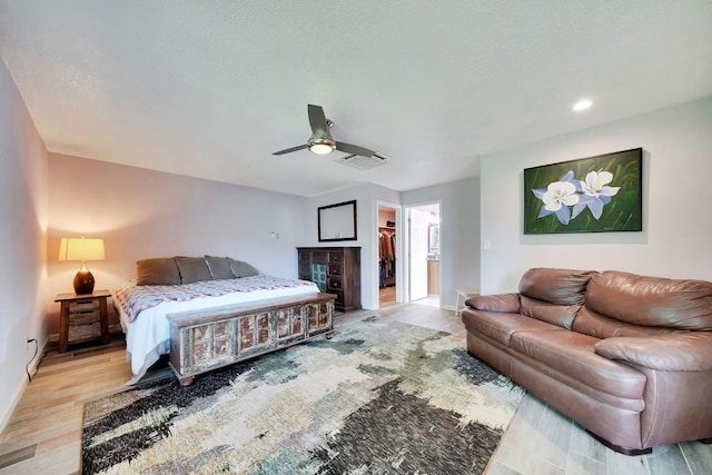 bedroom featuring light wood-type flooring, baseboards, visible vents, and a spacious closet