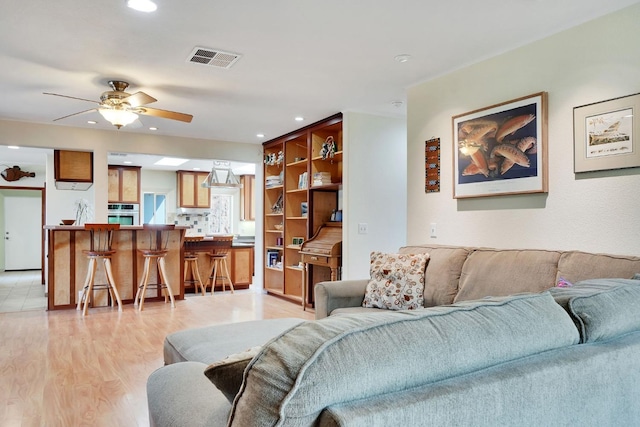 living area with ceiling fan, light wood-style floors, visible vents, and recessed lighting
