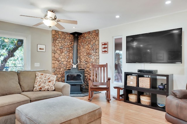 living area featuring light wood-type flooring, a wood stove, and ceiling fan