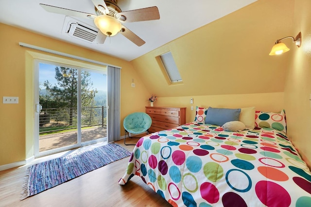 bedroom featuring vaulted ceiling with skylight, wood finished floors, baseboards, access to outside, and visible vents
