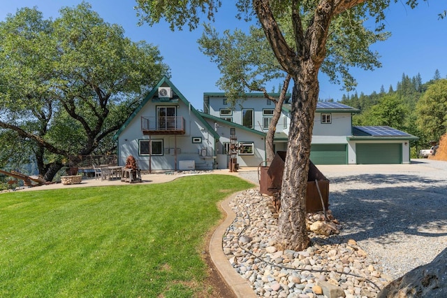 view of front facade with a fire pit, gravel driveway, a front yard, and a balcony