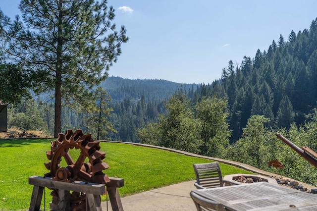 view of community with a view of trees, a yard, and a patio