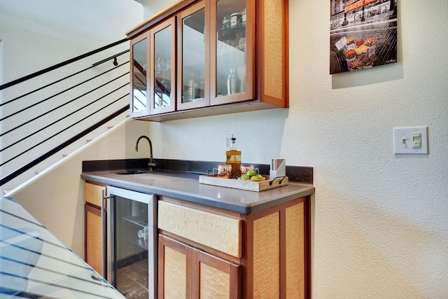 bar with a textured wall, a sink, indoor wet bar, and wine cooler