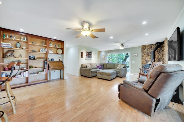 living room featuring a ceiling fan, a wood stove, light wood-style floors, and recessed lighting