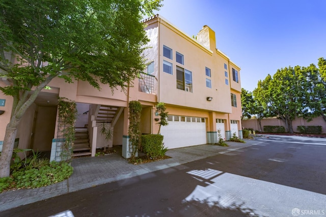 981 Asilomar Ter Unit 1, Sunnyvale, CA 94086 - view of front of home with stucco siding, stairs, a garage, and a chimney