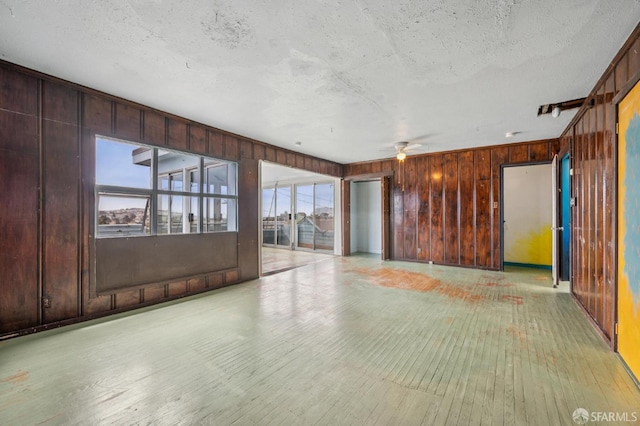 80 Bronte St, San Francisco, CA 94110 - empty room featuring plenty of natural light, wood walls, ceiling fan, light wood-style flooring, and a textured ceiling