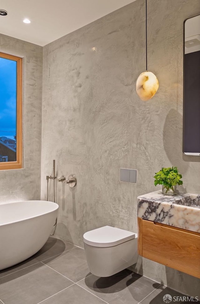 full bath with a freestanding tub, tile patterned floors, vanity, and toilet